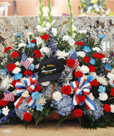 Honor that special Patriot with this sprawling flow of red, white and blue flowers, ribbons, and flags. A true American tribute. (hat not included.)