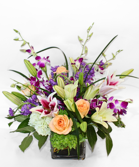 Purple dendrobium orchids, peach roses, green hydrangea and more in a leaf-lined vase